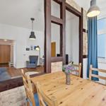 Dining room with wooden table and chairs. Passage to living area with sofa and armchair.