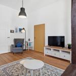 Living room with TV, armchair, and wooden floor. A room with modern furnishings.