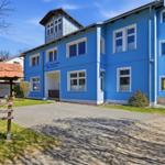 Blue-painted house with multiple windows and entrance area.