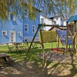 Backyard with playground, picnic table, and seating area under trees.