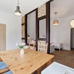 Esszimmer mit Holztisch und Stühlen, Blick in Schlafzimmer mit Bett und Holzbalken.