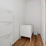 Ein Raum mit weißem Schrank, weißem Kinderbett und Holzboden.