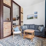 Wohnzimmer mit Sofa, Stuhl und Teppich. Holzfußboden und Fenster mit Vorhang.