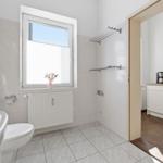 Bathroom with toilet, sink, and window. Passage to kitchen with worktop.