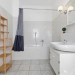 Bathroom with bathtub, sink, and wooden shelf.