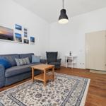 Living room with sofa, armchair, table, and rug on wooden floor.