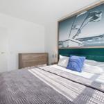 Schlafzimmer mit Bett, Kopfteil und Wandbild eines Segelboots.