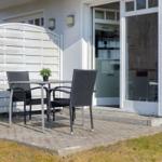 Terrasse mit Tisch und zwei Stühlen vor der Haustür.