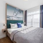 Schlafzimmer mit Bett, Wandbild und Fenster mit Vorhängen.