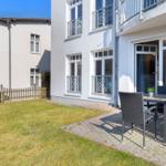 Hinterhof mit Garten, Terrasse und Sitzgelegenheiten. Haus mit Balkon und Fenstern.