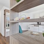 Küche mit Arbeitsplatz und Aufbewahrungsbereich. Holzoptik und weiße Schränke.