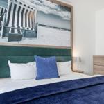 Schlafzimmer mit Bett, Nachttischen und Wandbildern.