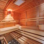 Holzsauna mit mehreren Sitzbänken und einem Eimer mit Löffel.