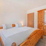 Schlafzimmer mit Holzbett, Nachttisch und Kleiderschrank.