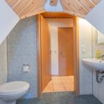 Badezimmer mit Toilette, Waschbecken und Dusche unter Dachschrägen.