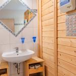 Badezimmer mit Waschbecken, Spiegel und Holzwand