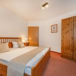Schlafzimmer mit Holzbett, Kleiderschrank und Nachttisch.
