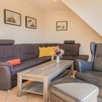 Wohnzimmer mit Sofa, Sessel und Couchtisch. Wandbilder und Uhr an der Wand.