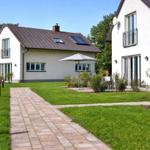 Haus mit Garten, Terrasse und Sonnenschirm. Pflasterweg führt zum Eingang.