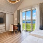 Schlafzimmer mit Blick auf See, Schreibtisch, Bett und TV.