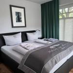 Schlafzimmer mit Doppelbett, grünen Vorhängen und Fenster mit Blick auf Bäume.