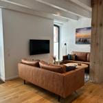 Wohnzimmer mit braunen Ledersofas, Holzboden und Fernseher an der Wand.