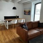 Ein Wohn- und Essbereich mit braunem Sofa, Esstisch und Holzboden.