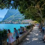 Lange Promenade entlang des Sees mit Bäumen und Blick auf die gegenüberliegende Uferseite.