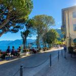 Promenade entlang des Sees mit Bäumen, Restaurants und Blick auf die Berge.