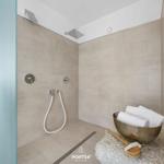 Dusche mit Regenduschkopf und Handbrause, daneben Metallwanne mit Handtüchern.
