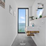 Badezimmer mit Blick aufs Meer, Spiegel und Waschbecken