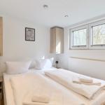 Schlafzimmer mit Doppelbett, zwei Nachttischen und Fenster mit Blick auf Wald.