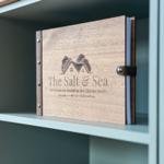 Holzmappe mit Logo und Adresse in Küchenregal