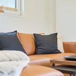 Orange Ledersofa mit Kissen und Tisch im Wohnbereich.
