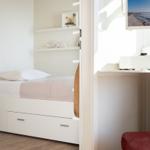 Bedroom with bed, closet, and TV on the wall.