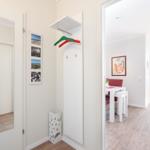 Entryway with mirror, coat rack, and view into dining area with table and chairs.