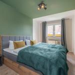 Schlafzimmer mit Bett, grüner Wand und Fenster.