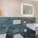 Bad mit Waschbecken, Spiegel und Buddha-Figur an der Wand.