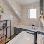 Bad mit Badewanne, Waschbecken und Fenster unter Dachschräge.