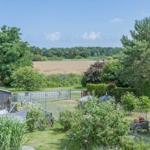 Garten mit Grill, Pflanzen und Blick auf Felder und Bäume.