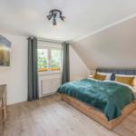 Schlafzimmer mit Bett, Fenster, TV und Nachttisch.
