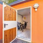 Eingangstor zu einer Garage mit Fahrrädern und Außenbeleuchtung an orangefarbener Wand.
