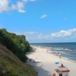 Strand mit Rettungswache, Sandstrand, Meer und bewölktem Himmel.