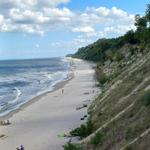 Strand mit Sand und Meer unter blauem Himmel mit weißen Wolken.