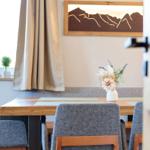 Essbereich mit Holztisch, grauen Stühlen und Wandbild mit Bergmotiv.
