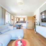 Wohnzimmer mit Sofa, TV und Küchenbereich im Hintergrund.