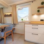 Küche mit Essbereich, Fensterblick auf Berge, Holztische, Stühle und Schränke.
