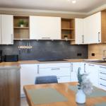 Moderne Küche mit Holz- und Weißfronten, Arbeitsplatte und Essbereich.