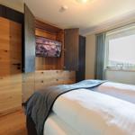 Schlafzimmer mit Doppelbett, integriertem Fernseher und Fenster mit Blick.
