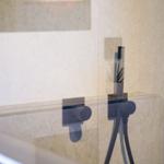 Duschkopf und Armaturen in moderner Dusche mit Glaswand und dekorativen Wänden.